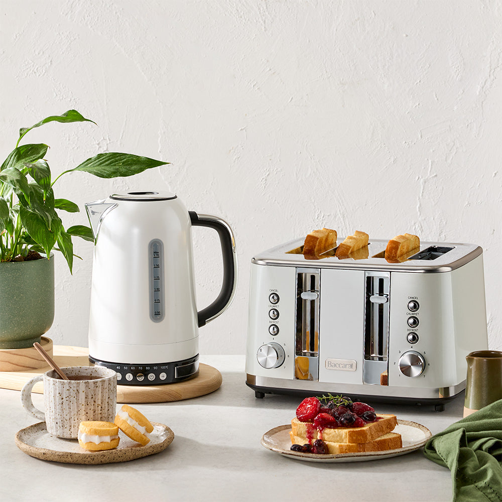 A white electric kettle and a white four-slice toaster are displayed together on a light countertop alongside breakfast items.