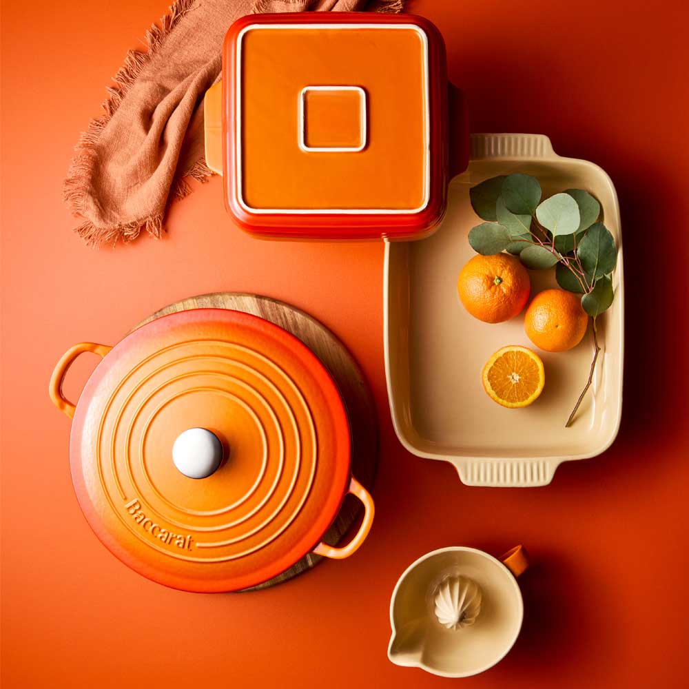 Ceramic cookware with orange accents on a warm-toned background