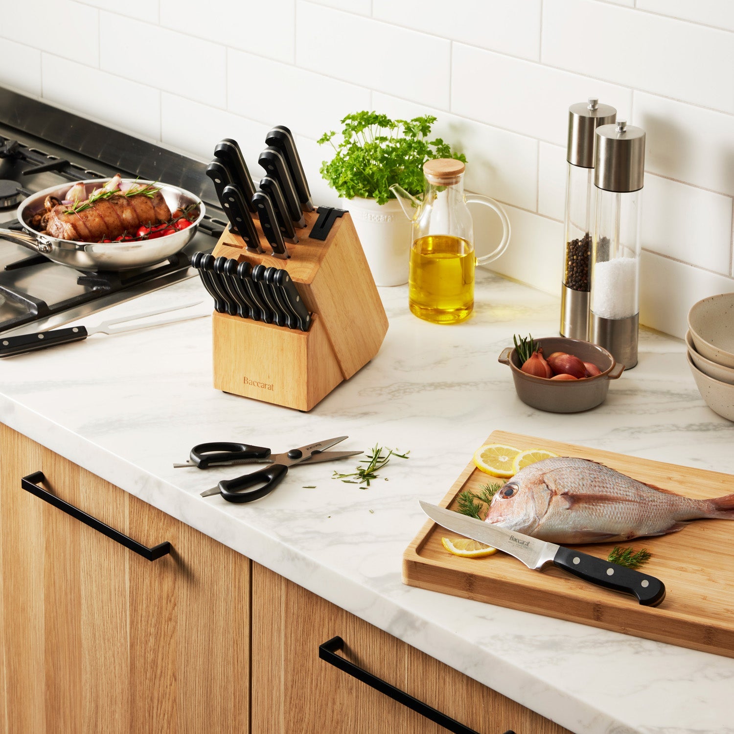 A selection of Sabre kitchen knives and scissors on cutting board with herbs and handles - Baccarat 