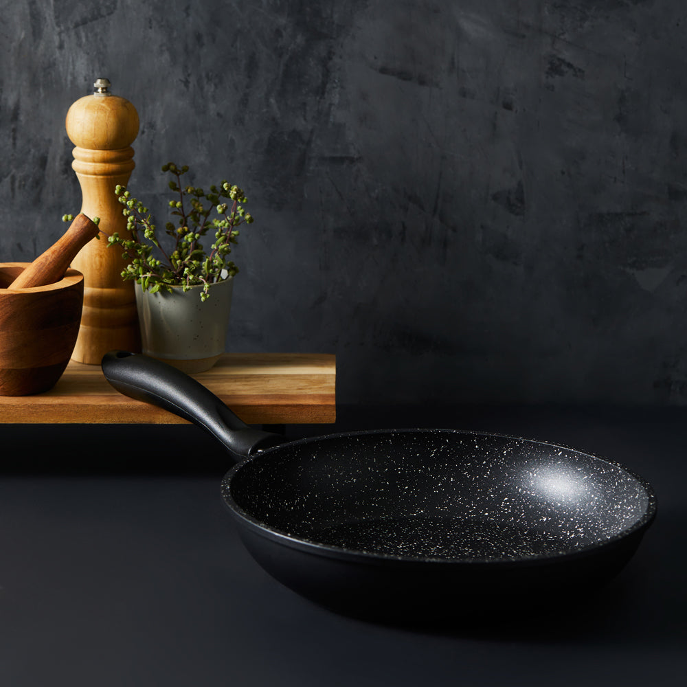 Hand holding a frying pan with grilled salmon and lemon slices - stone frypan 28cm - Baccarat
