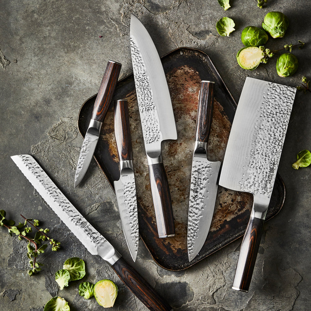 A stunning Baccarat Damashiro Emperor 15 cm chef's knife on a dark cutting board with green veggies