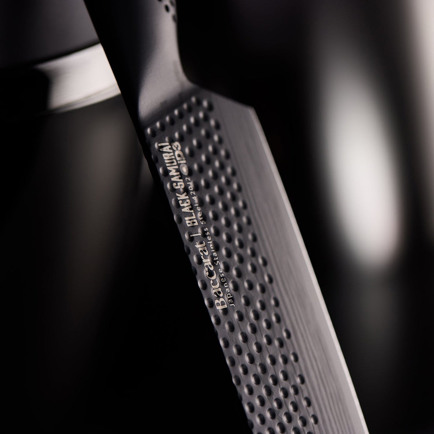 A top-angle view of sleek black knives with precision blades arranged vertically - Baccarat Samurai