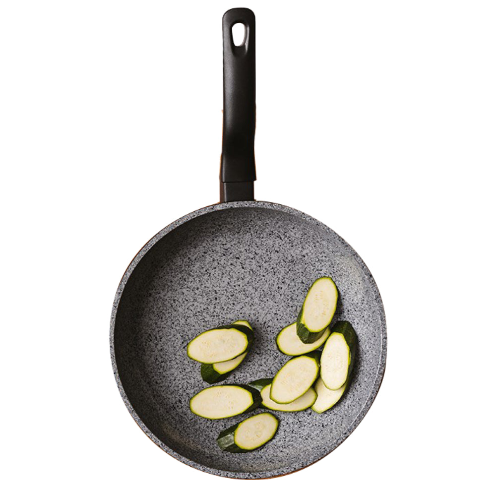 A gray speckled non-stick frying pan with a black handle, shown from a top-down view, containing sliced zucchini on a solid white background.