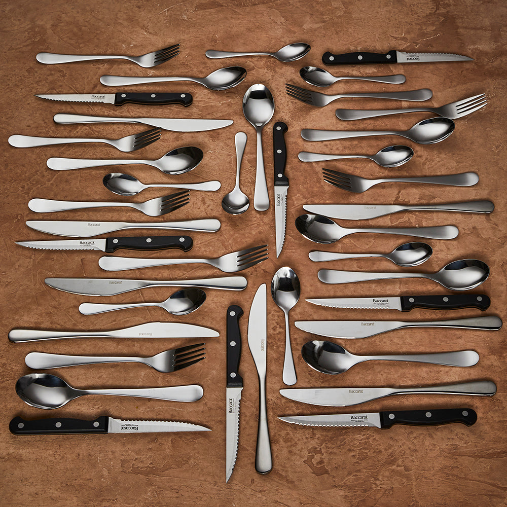 A 40 piece cutlery set gleams on a brown napkin showcasing luxury tableware - Baccarat sabre mainz