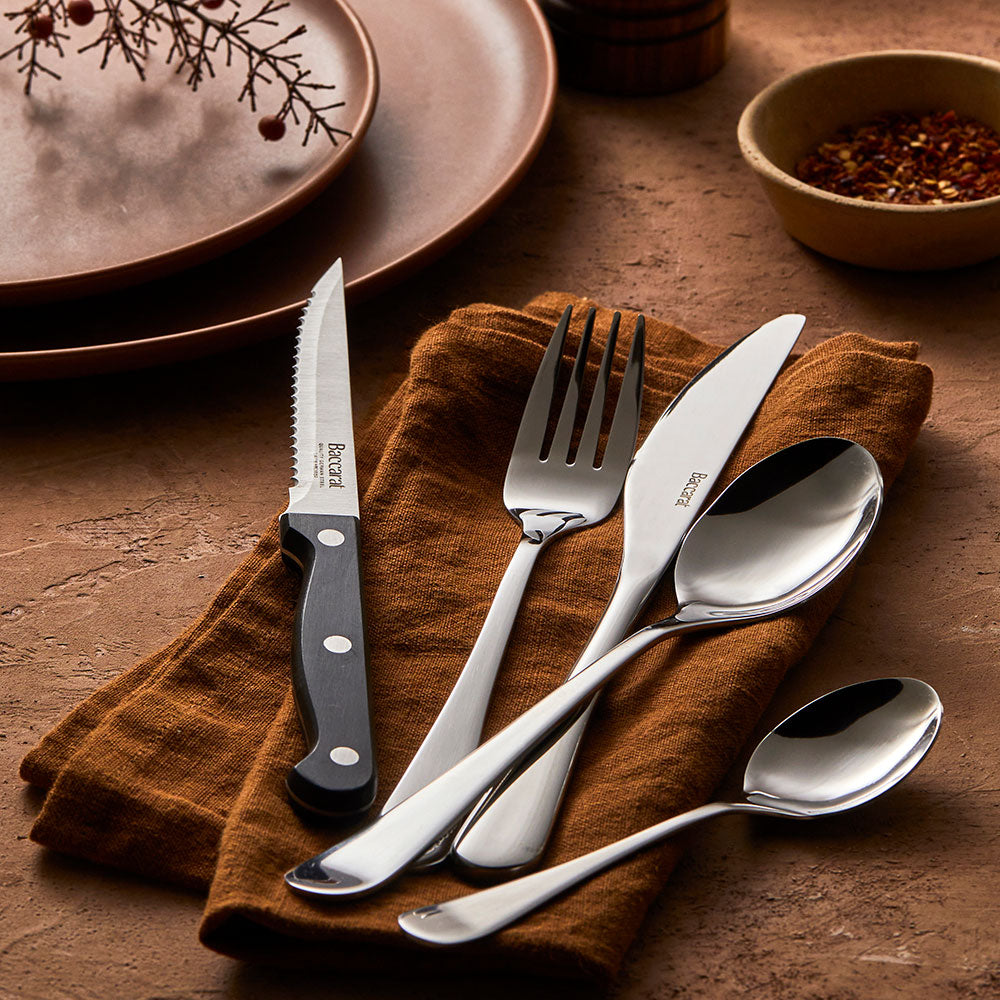 A 40 piece cutlery set gleams on a brown napkin showcasing luxury tableware - Baccarat sabre mainz