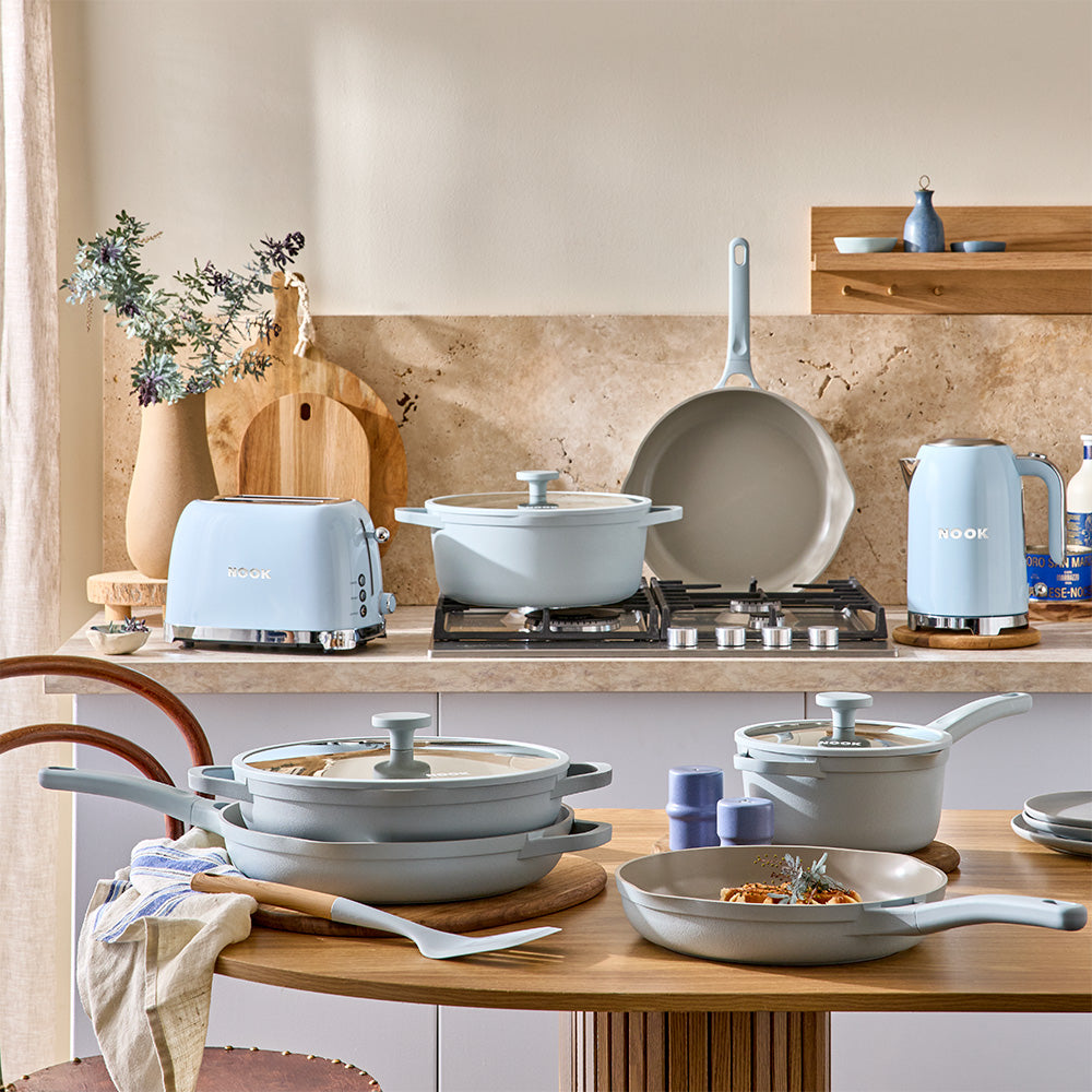 A wide shot shows a modern kitchen arranged with various light blue cookware pieces and matching appliances.