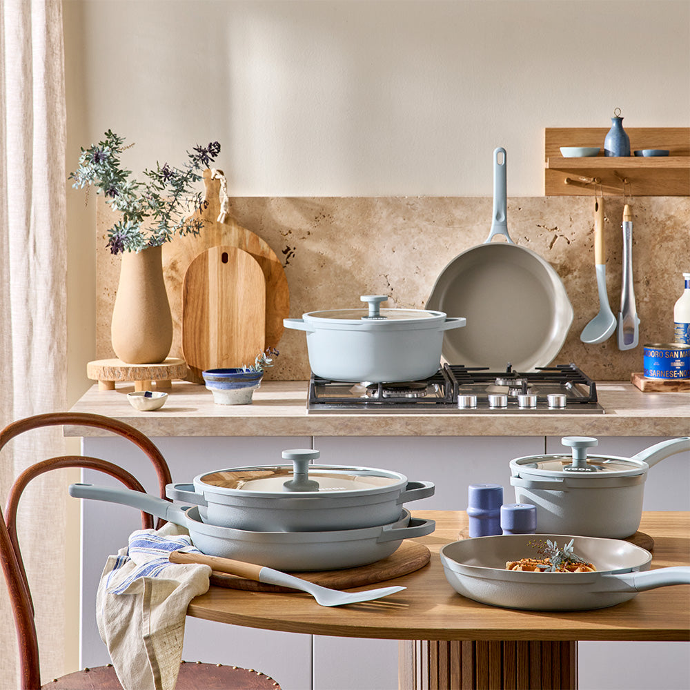 A collection of light blue cookware items is displayed across a kitchen table and countertop setting.