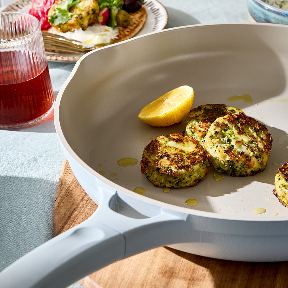 A close-up view focuses on cooked patties inside a light blue skillet resting on a wooden trivet.