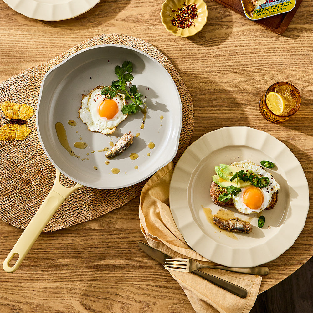 A  pastel yellow frypan filled with cooked food, topped with green chili 