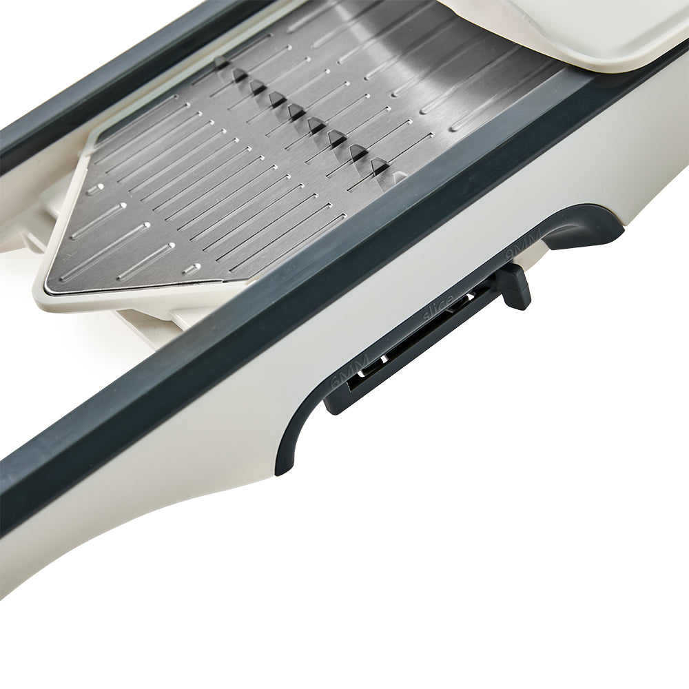 A close-up angle captures the embedded V-shaped blade and the textured stainless steel sliding surface of the slicer.