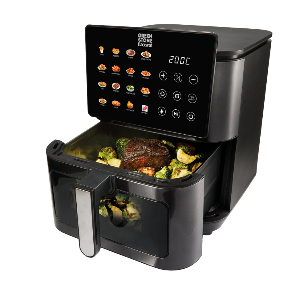 An open black air fryer basket filled with roasted meat and vegetables is angled against a solid white background.