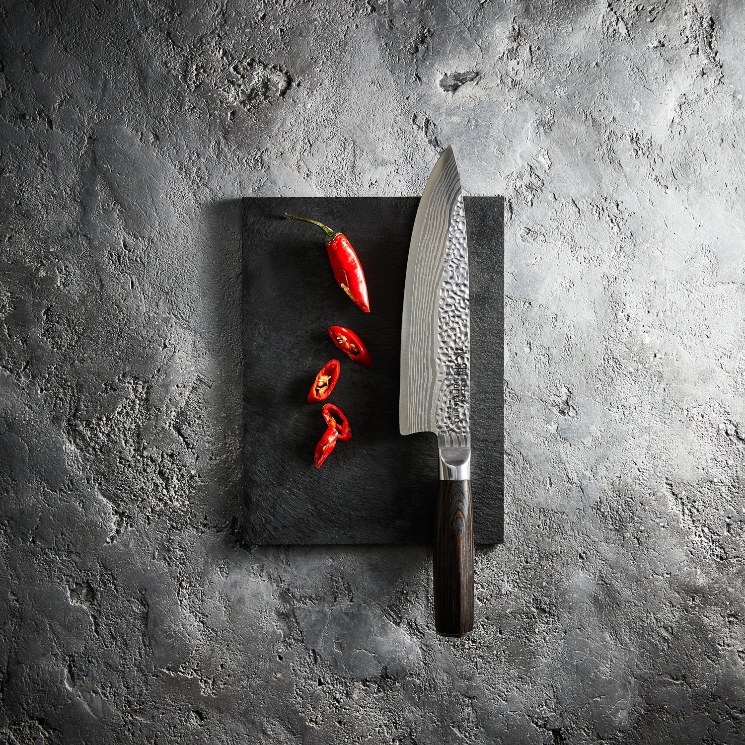 Sliced red peppers on a stone board with a sharp knife - Baccarat damashiro emperor chefs knife 20cm