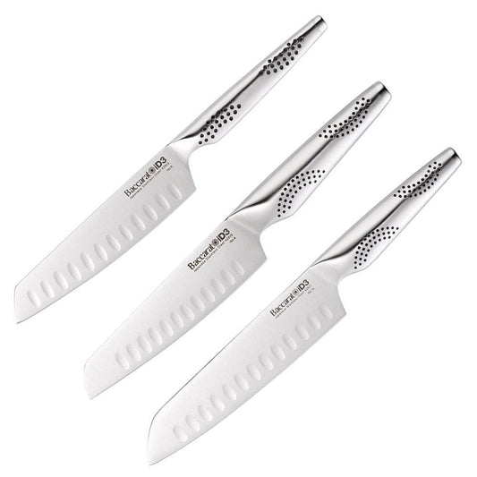 Three santoku knives resting on a wooden cutting board with fresh herbs and vegetables - Baccarat