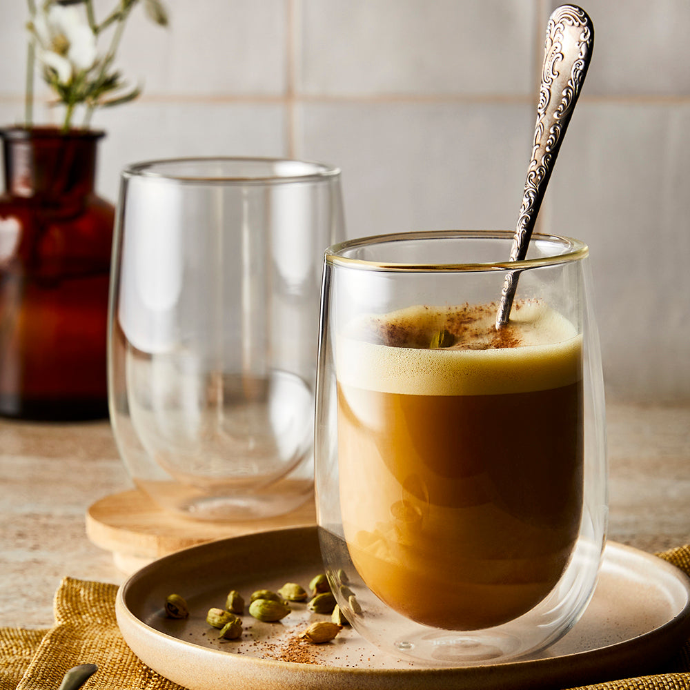 hot coffee in double-walled glass mug on wooden plate with spoon next to empty glass - Baccarat