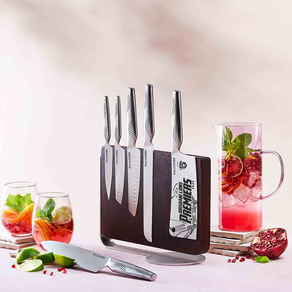 Sharp stainless steel kitchen knives with lime slices and cocktails on a pink surface - Baccarat