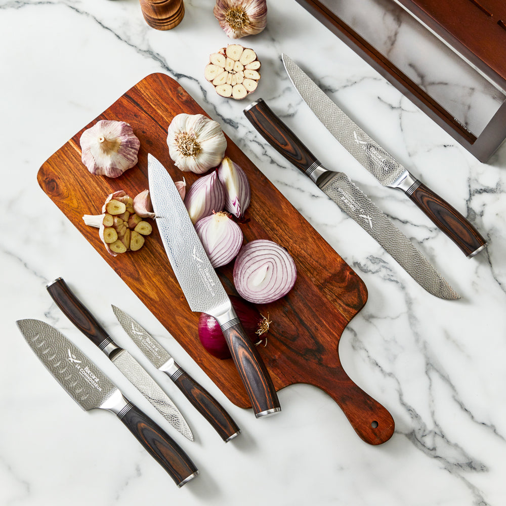 Chef's knife slicing garlic on a kitchen counter shiny silver blade 7 piece knife block - Baccarat
