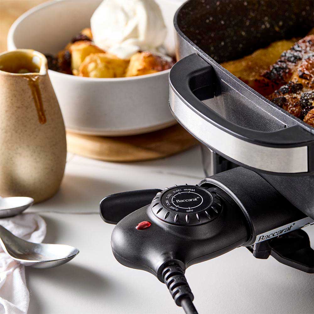 A black pan of bread pudding with a bowl of ice cream on a white countertop black frypan - Baccarat
