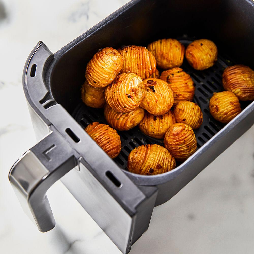 Close-up of a sleek black loaf bread maker with removable baskets and cooked potatoes - Baccarat