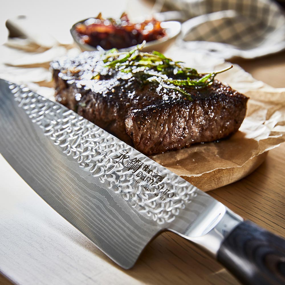 Person slices steak on a wooden board wearing blue-striped apron ideal for kitchen tasks - Baccarat