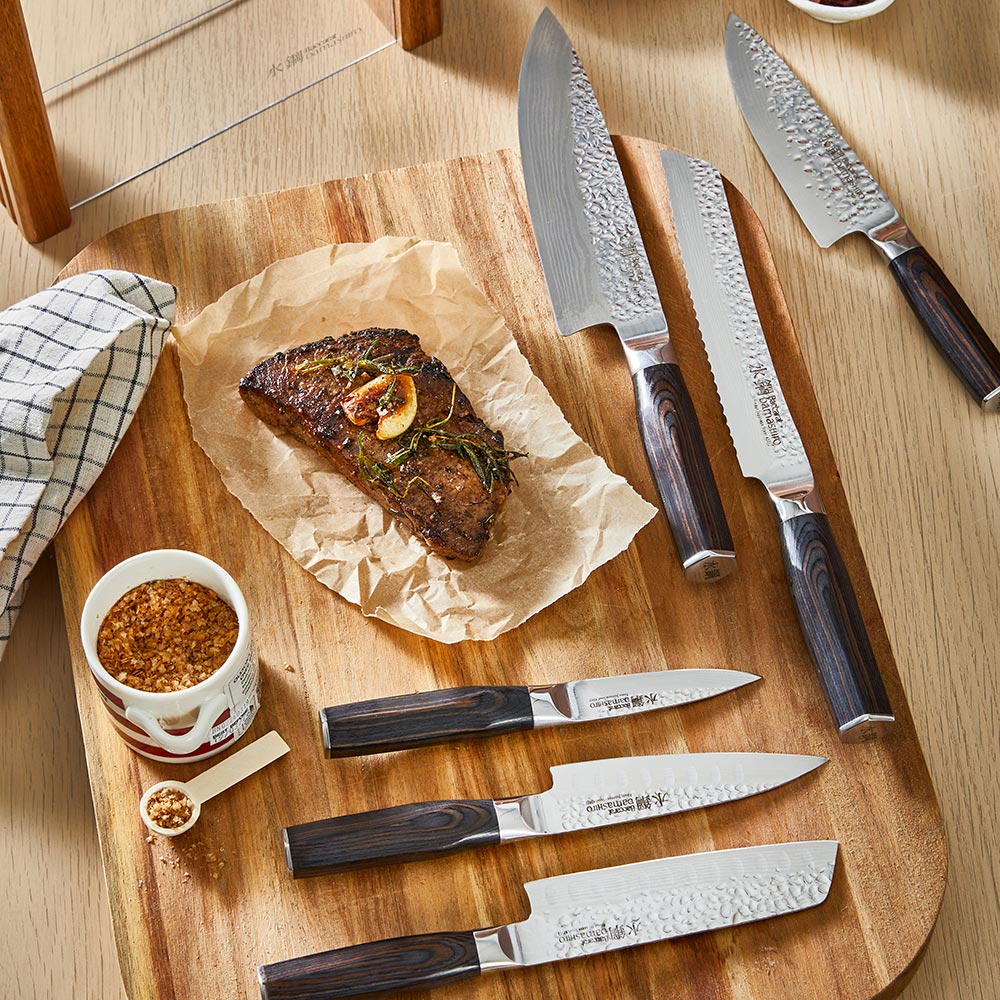 Person slices steak on a wooden board wearing blue-striped apron ideal for kitchen tasks - Baccarat