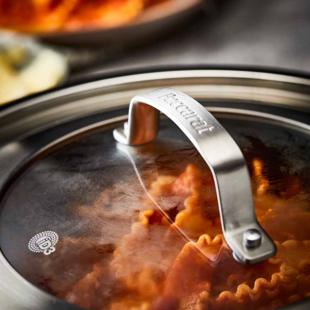 Close-up of a Baccarat id3 Saute Pan 28cm frypan with a glass lid and steam featuring silver handle