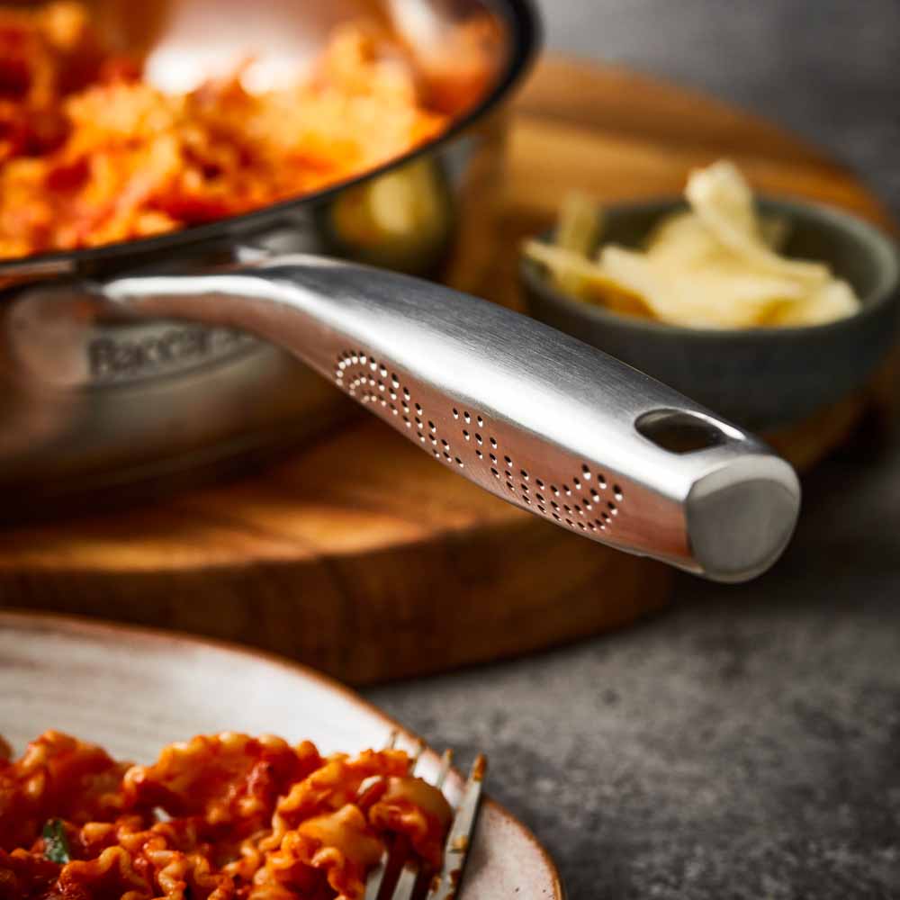 Close-up of a Baccarat id3 Saute Pan 28cm frypan with a glass lid and steam featuring silver handle