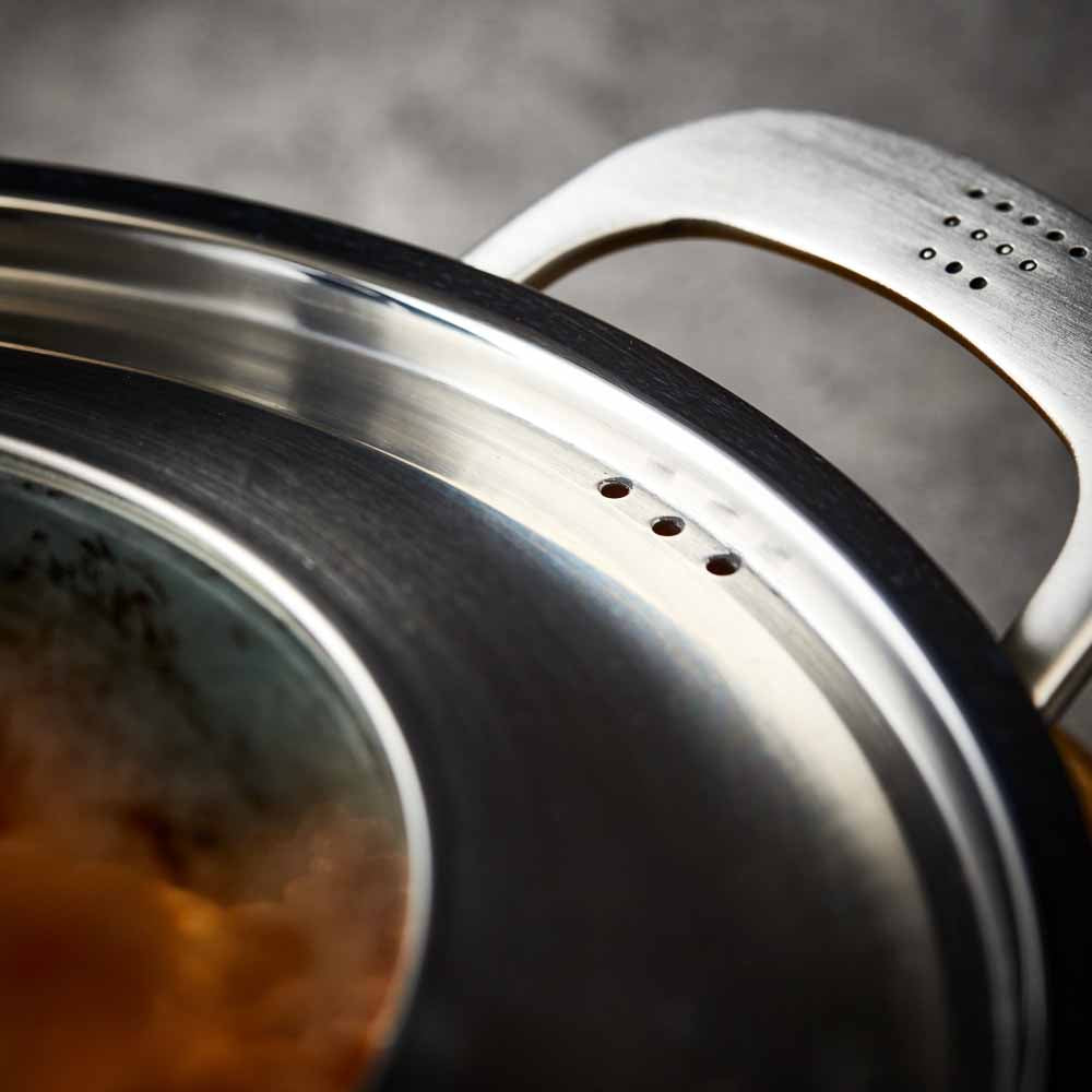Close-up of a Baccarat id3 Saute Pan 28cm frypan with a glass lid and steam featuring silver handle