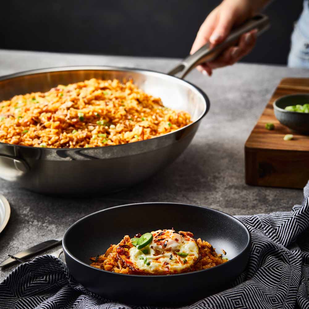 Person serving gourmet pasta from a black bowl - Baccarat id3 stainless steel chef pan with lid 32cm