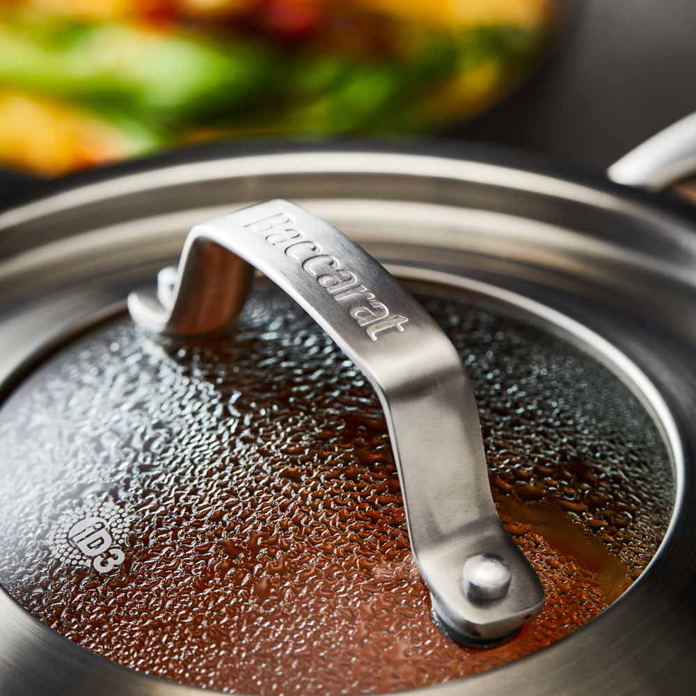 stainless steel saucepan 20cm pot of soup on a wooden board beside black bowl of noodles  - Baccarat