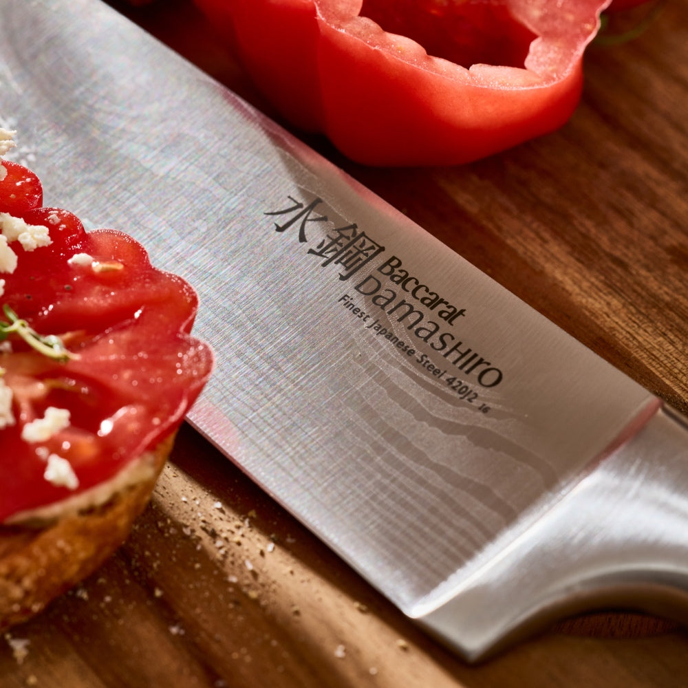 Baccarat Damashiro knife on a wooden cutting board with sliced tomatoes