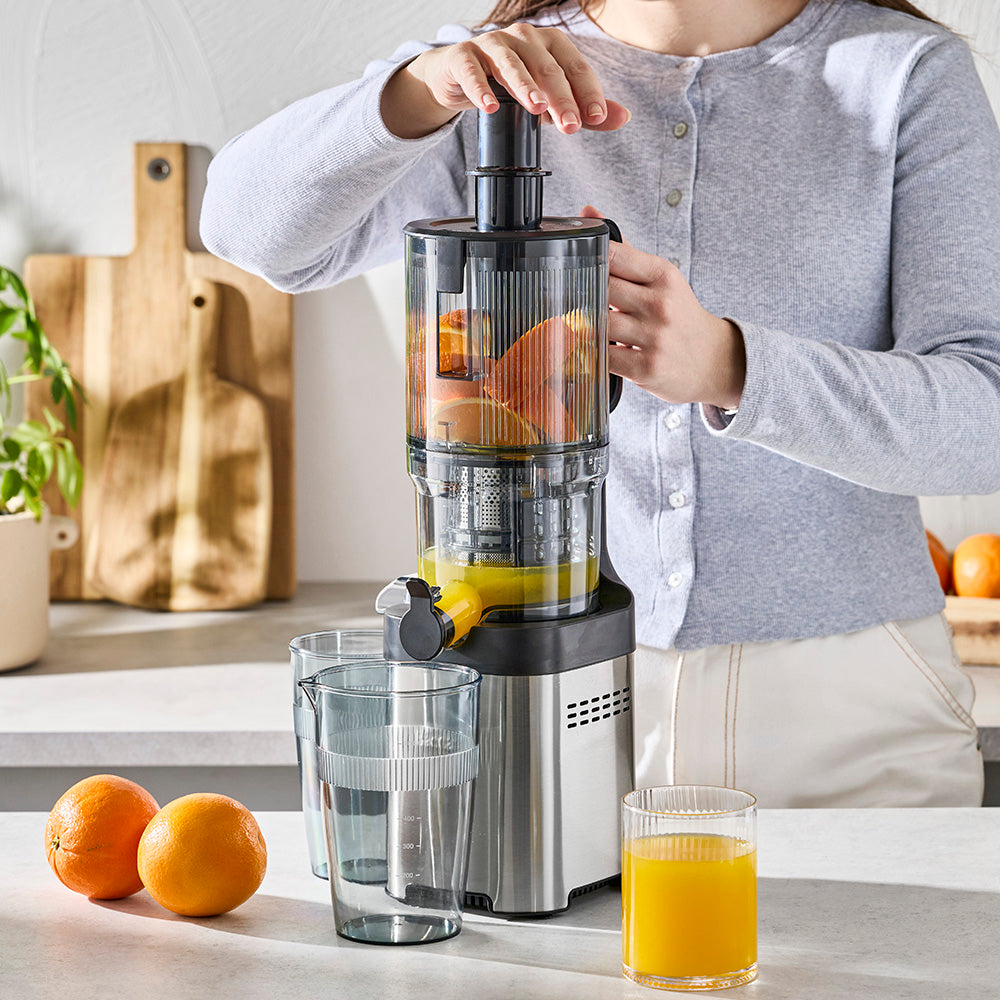Person using a manual juicer to extract juice from oranges in a kitchen setting.