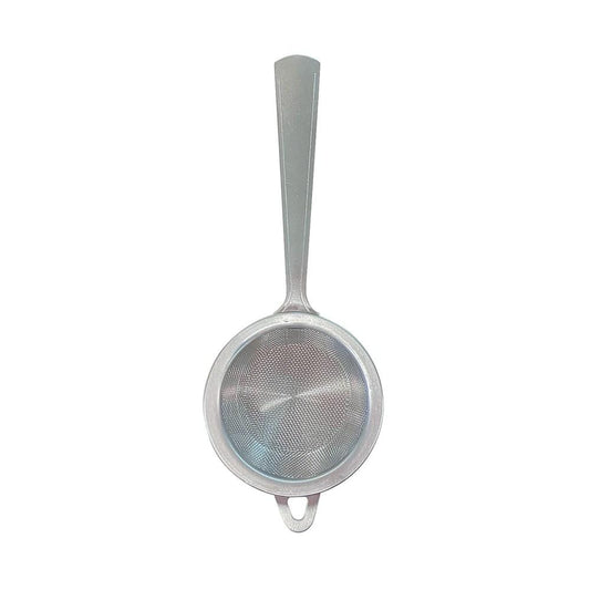 A stainless steel tea strainer with a handle beside a stylish bowl - Baccarat tea house