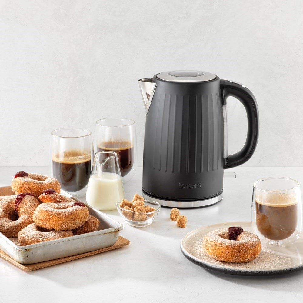 Black kettle pours hot water into a white cup beside a pastry plate - Baccarat  Boiling Point Kettle