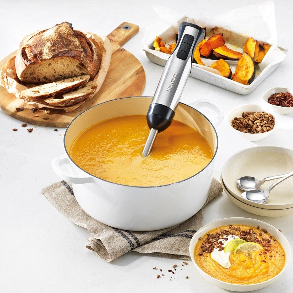 A yellow smoothie is blended surrounded by fresh fruits with a Baccarat The Quick Mix Stick Blender