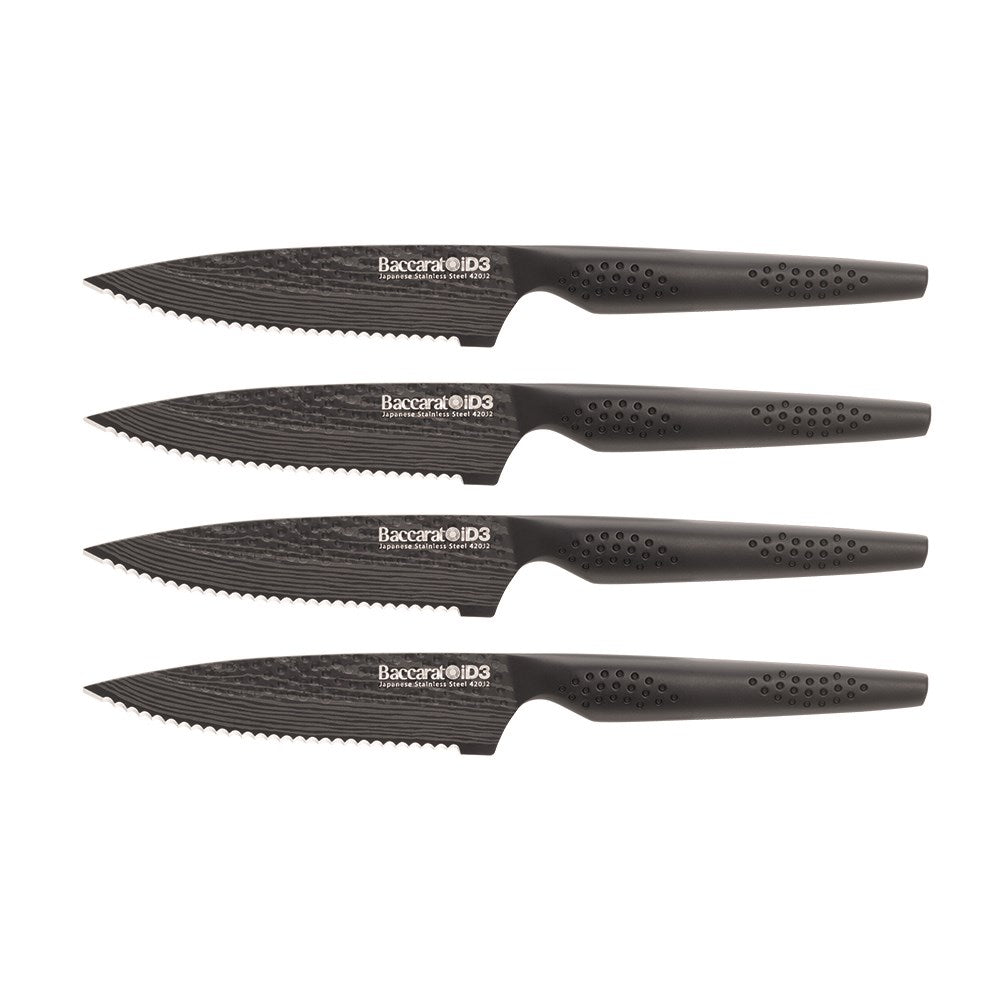 Elegant Baccarat Samurai Set of 4-piece steak knives lined up on dark slate with herbs and spices